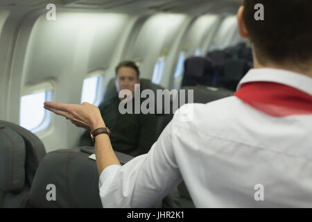 Hôtesse de l'air donne les consignes de sécurité à bord d'un avion Banque D'Images