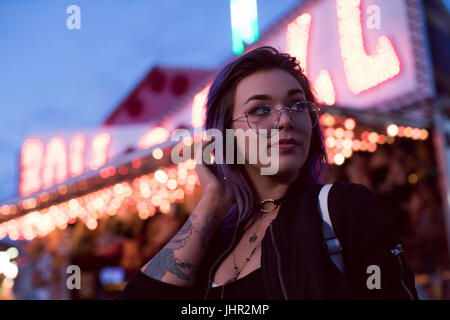 Thoughtful woman standing in amusement park at Dusk Banque D'Images