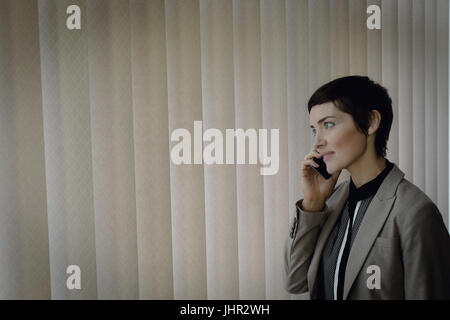 Beautiful businesswoman talking on mobile phone in office Banque D'Images