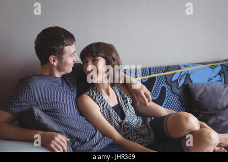 Smiling couple relaxing on sofa in living room à la maison Banque D'Images