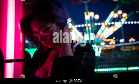 Belle femme debout dans un parc d'attractions de nuit Banque D'Images