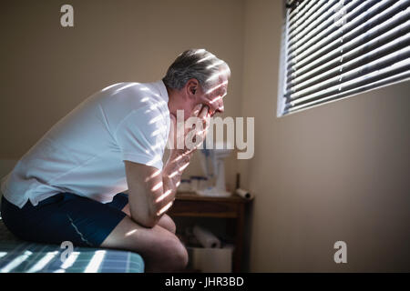 Vue latérale d'happy male patient sitting on bed at Hospital ward Banque D'Images