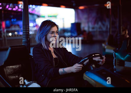 Belle femme assise en voitures de butoir en amusement park Banque D'Images