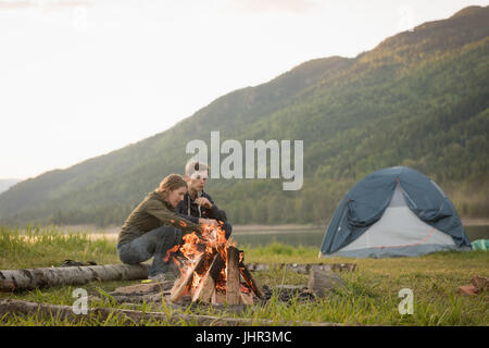 Jeune couple assis près de camp de camping Banque D'Images