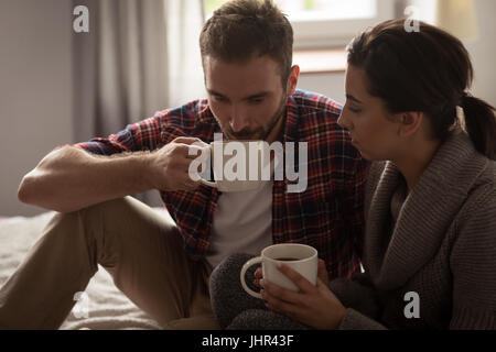 Young couple having coffee while sitting on lit dans la chambre à la maison Banque D'Images
