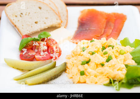 Set de petit-déjeuner, des œufs brouillés à la ciboulette, le poisson, le concombre, la tomate et le pain Banque D'Images