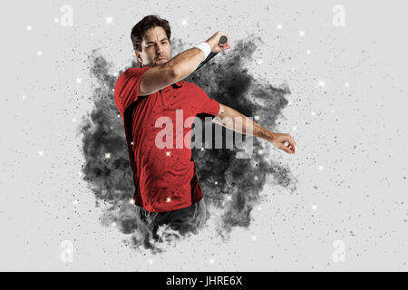 Joueur de tennis avec un uniforme rouge qui sort d'une explosion de fumée . Banque D'Images