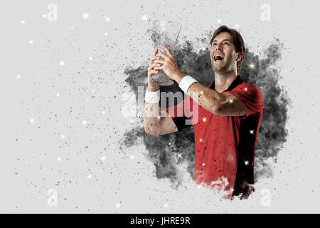 Joueur de tennis avec un uniforme rouge qui sort d'une explosion de fumée . Banque D'Images