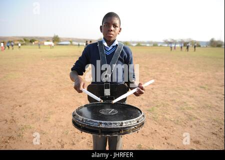 Un jeune garçon africain joue la batterie dans un champ vide au cours de l'aérospatiale et de la défense de l'Afrique de l'Expo le 18 septembre 2012 à Pretoria, Afrique du Sud. (Photo de Benjamin Wilson par Planetpix) Banque D'Images