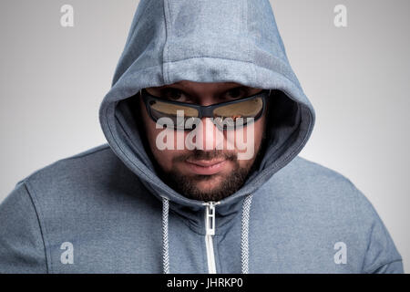 Un mystérieux homme barbu à lunettes caché sous un capot. Banque D'Images