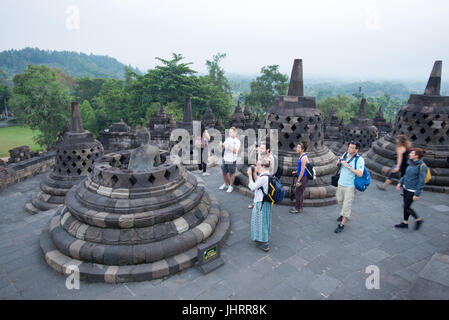 Les touristes sont en photo de invincible statue de Bouddha dans un stupa, Temple de Borobudur Java Indonésie. Banque D'Images