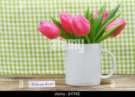 Bienvenue accueil carte avec mug plein de fleurs tulipe rose sur fond à carreaux Banque D'Images