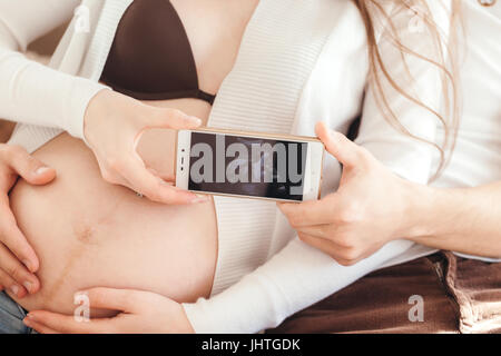 Jeune couple amoureux montrant une échographie photo de leur téléphone mobile bébé close up Banque D'Images