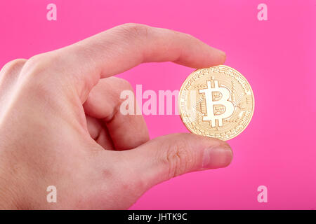 Man's hand holding Bitcoin or sur fond rose Banque D'Images