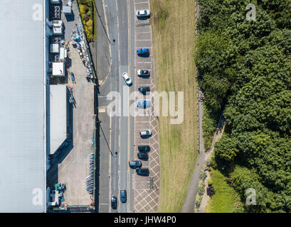 Une vue aérienne d'un bâtiment industriel commercial par une route principale et dense forêt verte avec sentier et parking, lignes de l'architecture par la nature Banque D'Images