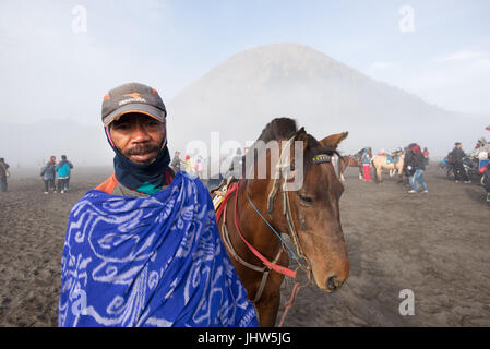 Les Indonésiens l'équitation dans une mer de sable dans le Mont Bromo est de Java en Indonésie. Banque D'Images