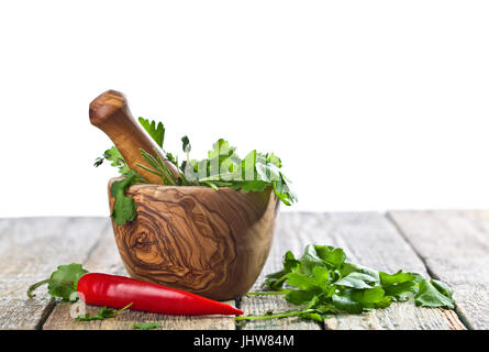 Différentes herbes sur une vieille table en bois . Mortier en bois avec le romarin, la coriandre, le thym et le persil.isolé sur fond blanc. Banque D'Images