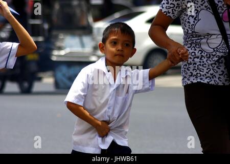 ANTIPOLO CITY, PHILIPPINES - Juillet 13, 2017 : un jeune étudiant promenades avec sa mère pour aller à l'école. Banque D'Images