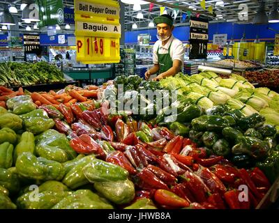 ANTIPOLO CITY, PHILIPPINES - 11 juillet 2017 : un travailleur prend des fruits et légumes frais sur une étagère dans une épicerie à Antipolo City. Banque D'Images