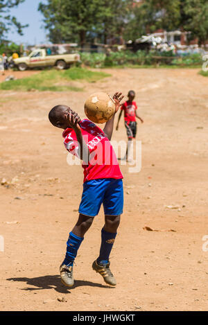 Les enfants de Kibera à jouer au football sur un terrain poussiéreux, Nairobi, Kenya Banque D'Images