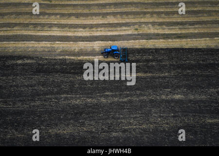 Cultiver du tracteur au champ du printemps, vue aérienne Banque D'Images