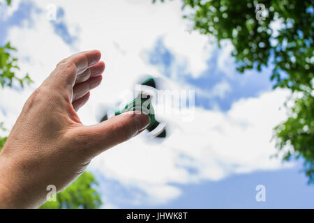 Côté masculin avec rotation fidget spinner against sky Banque D'Images