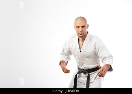 Jeune homme fighter en kimono blanc avec ceinture noire pour le judo, le jiu-jitsu posing in combat posent sur fond blanc isolé Banque D'Images