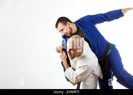 Deux jeunes hommes dans un kimono bleu et blanc lutte judo jiu jitsu , sur un cas isolé sur fond blanc
