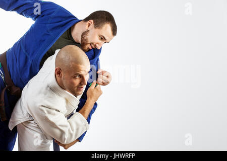 Deux jeunes hommes dans un kimono bleu et blanc lutte judo jiu jitsu , sur un cas isolé sur fond blanc