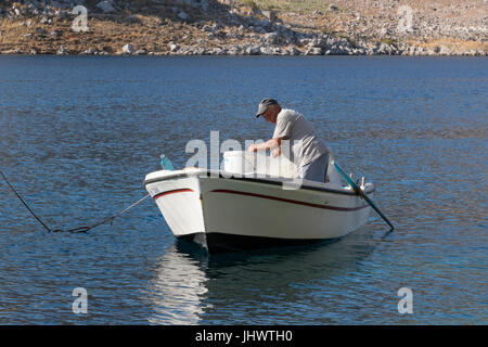 L'île de Symi, sud de la mer Egée, Grèce - - un pêcheur réparant ses filets à Pedi Banque D'Images