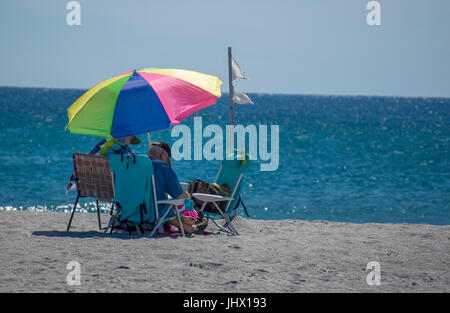 L'homme et de la femme se détendre dans des chaises longues sur une plage de Floride Banque D'Images