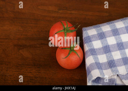 Deux tomates rouges frais, sur une table en bois avec des serviettes à carreaux bleu Banque D'Images