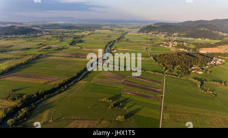 Vue aérienne de flexion de la rivière à travers champs au coucher du soleil. Banque D'Images