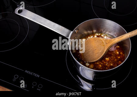 Casserole avec meltet sucre blanc sur une plaque de cuisson à induction Banque D'Images