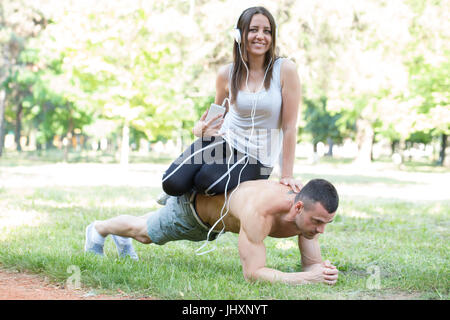 Jeune couple heureux, l'homme et de la femme, de l'exercice de travailler ensemble et de se préparer au concours. Ils effectuent l'acrobatie.Elle se cale sur son dos pendant qu'il était d Banque D'Images