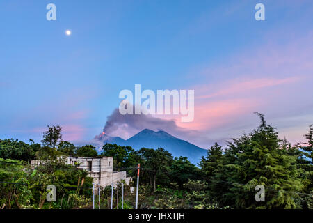 Poussée de fumée et de la lave en éruption du volcan de Fuego volcan acatenango à côté à l'aube sous la pleine lune près de Antigua, Guatemala, Amérique centrale Banque D'Images