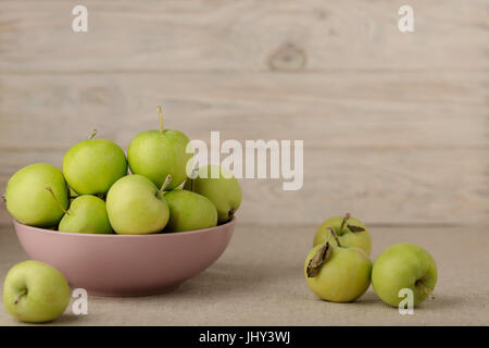 La pomme verte dans une plaque de lilas sur un fond clair en bois. Focus sélectif. Banque D'Images