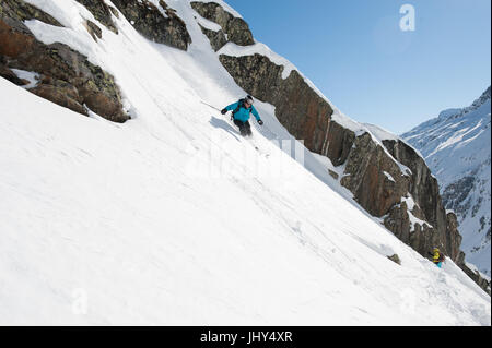 Croisière sur un skieur slop de poudre le long d'une ligne de rochers Banque D'Images