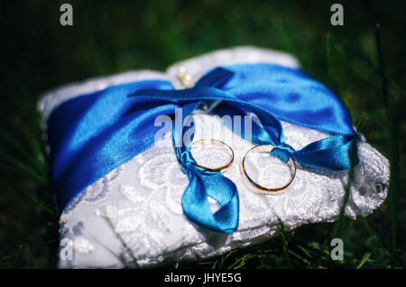 Les anneaux de mariage sur l'oreiller avec du ruban bleu Banque D'Images