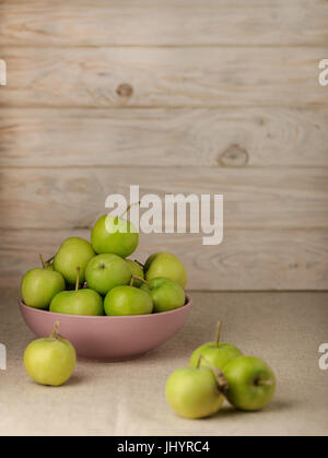 La pomme verte dans une plaque de lilas sur un fond clair en bois. Focus sélectif. Banque D'Images