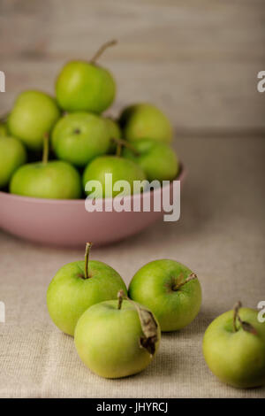 La pomme verte dans une plaque de lilas sur un fond clair en bois. Focus sélectif. Banque D'Images