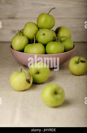 La pomme verte dans une plaque de lilas sur un fond clair en bois. Focus sélectif. Banque D'Images