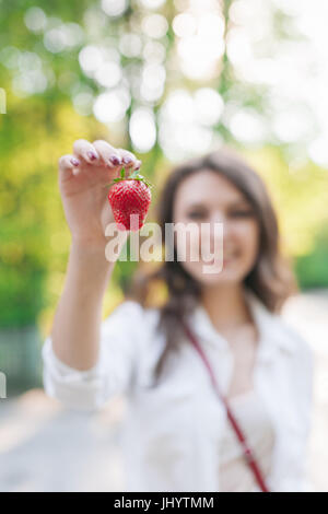 Smiling women hold de fruits rouges fraîchement fraises arrière-plan Banque D'Images