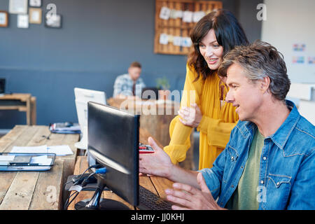 Smiling young office colleagues talking together sur un ordinateur Banque D'Images
