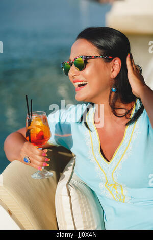 Happy woman bronzage et boire un cocktail au café du bord de mer, selective focus Banque D'Images