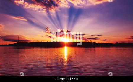 Incroyable coucher du soleil à Rio Madeira à Porto Velho RO le Brésil. Coucher du soleil à heure d'or avec quelques rayons de soleil, les ombres de nuages et les réflexions sur l'eau Banque D'Images