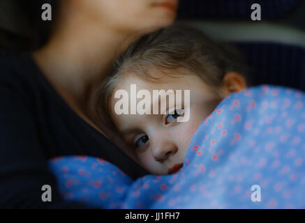 Petite fille en train de dormir dans les bras de sa mère Banque D'Images