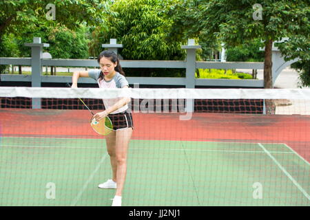 Fille de service sur un match de badminton sur la cour à l'extérieur Banque D'Images