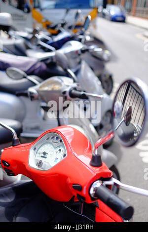 Un scooter Vespa rouge garée dans une rangée de scooters près de la gare de Euston, Londres Banque D'Images