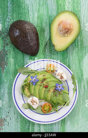 Toasts à l'avocat et saumon fumé sur la plaque blanche sur l'ancienne en bois green craked board avec l'avocat de moitié à l'arrière Banque D'Images